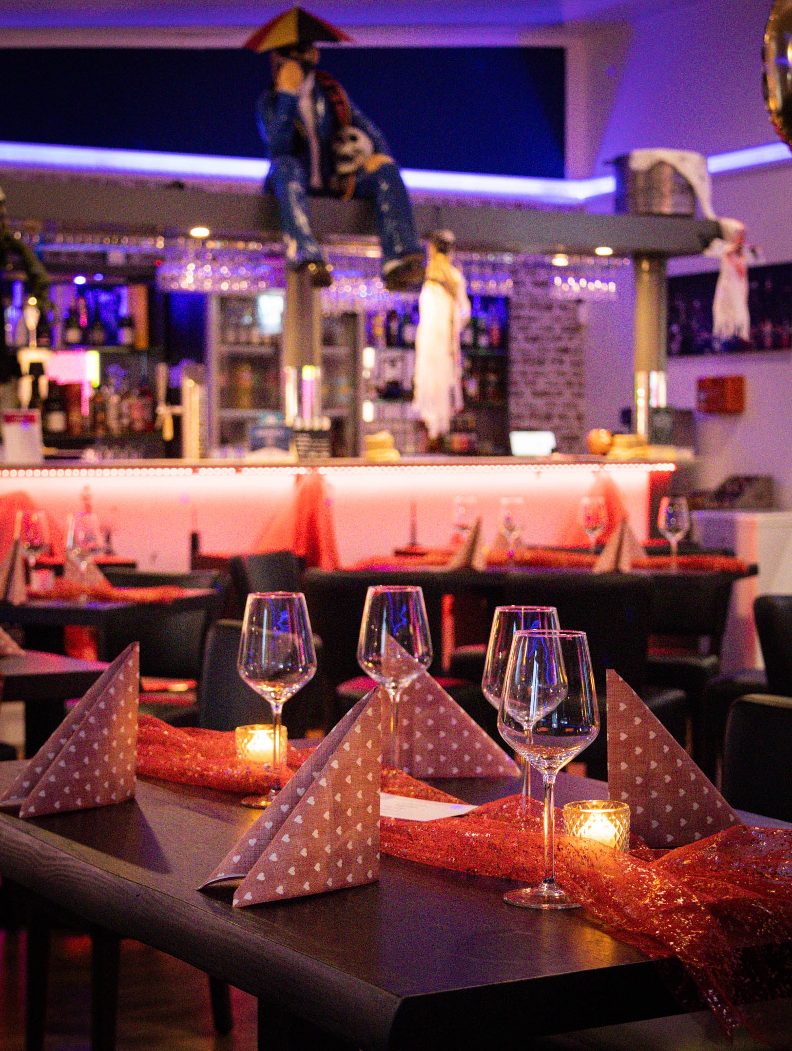 Festlich gedeckte Tische mit roter Dekoration vor der Bar